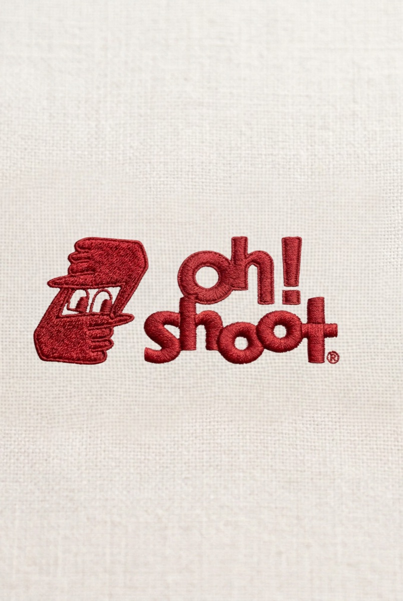 oh!shoot logo embroidered in red on white fabric